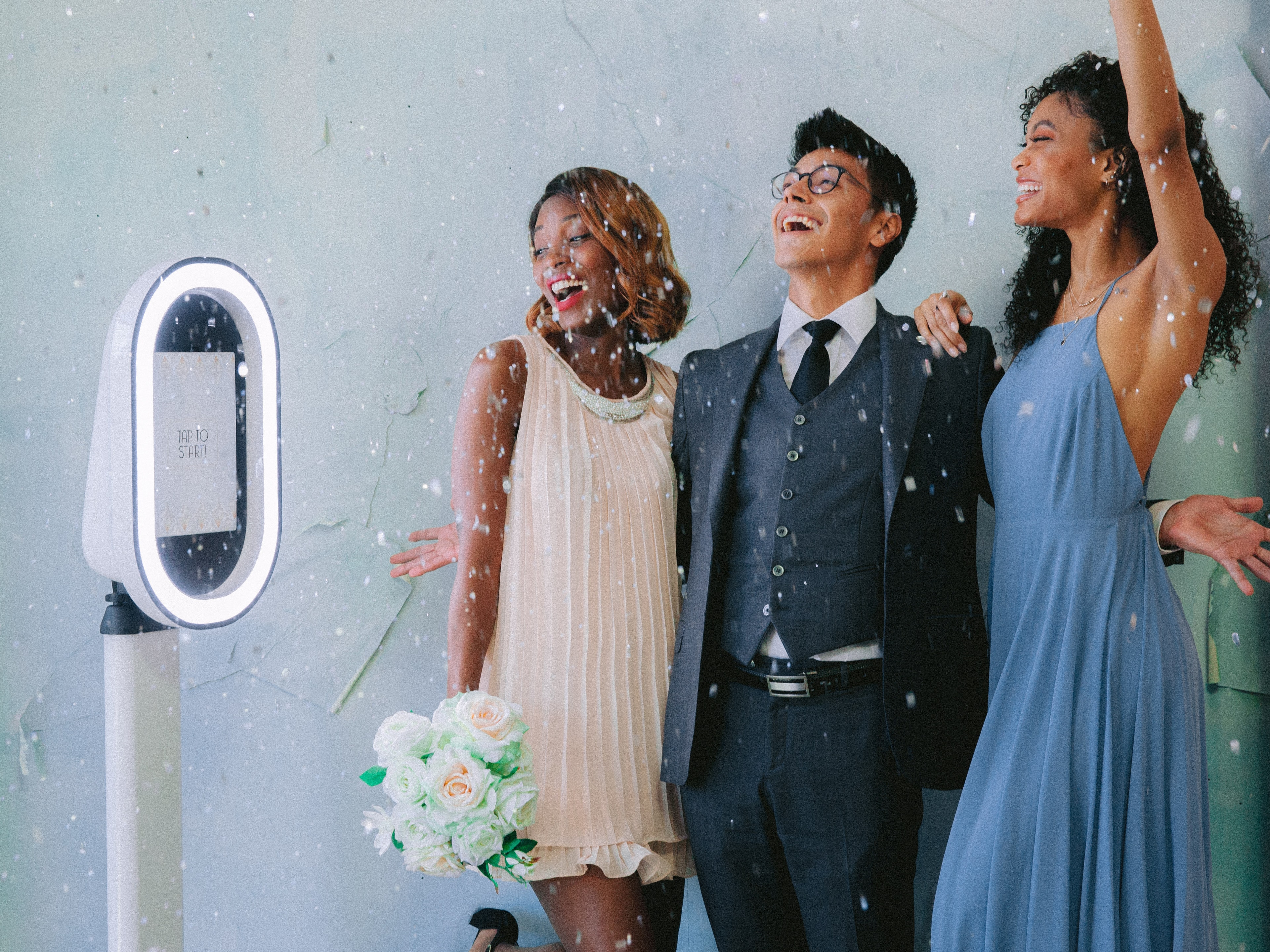 Guests posing beside the GrinBin photobooth under string lights